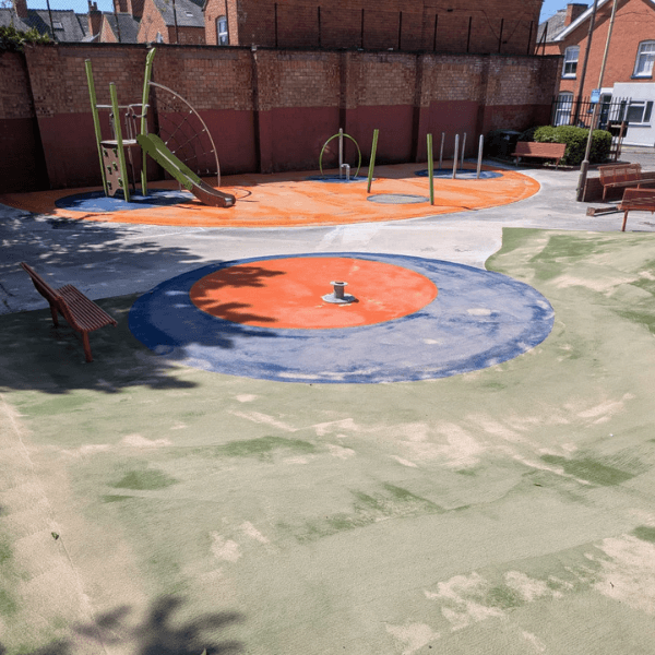 Playground with slide, climbing frame, roundabout and poles on bright orange surfacing.